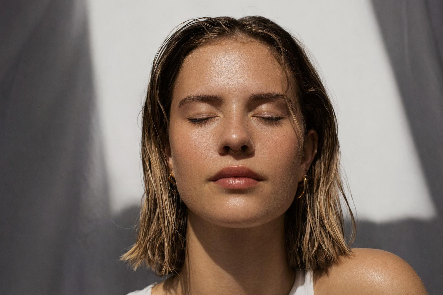 Woman with closed eyes against a neutral background